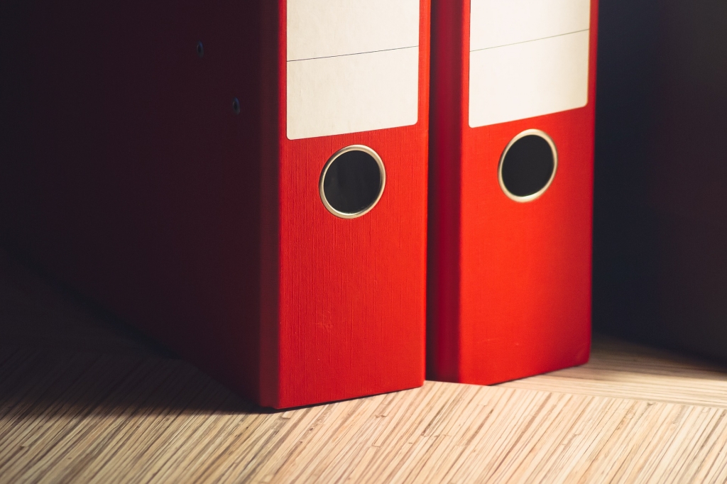 two red binders standing side-by-side on a table