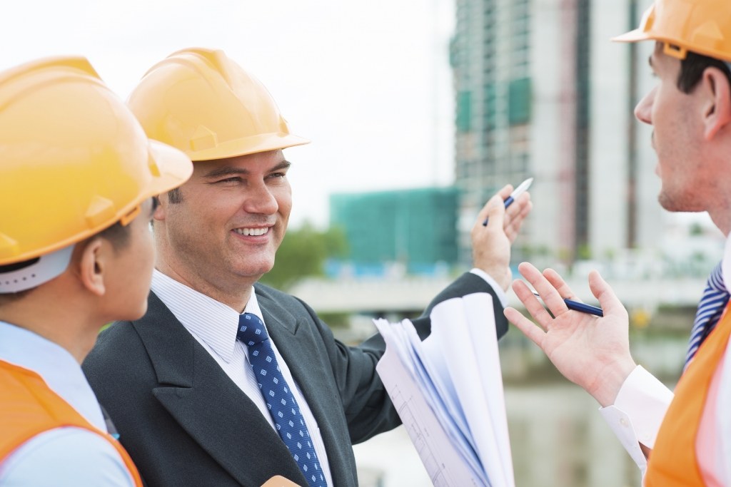 Three constructors discussing project of the building outside