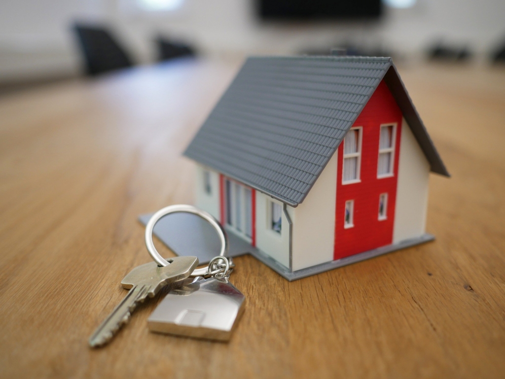 Little toy house with keys on wood table