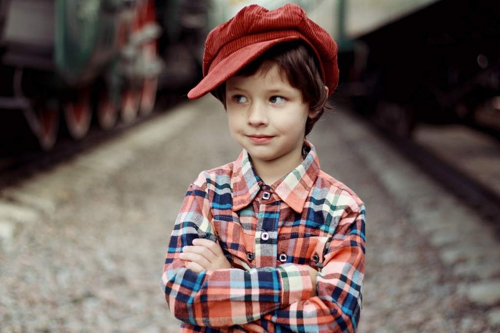 close up of boy with arms crossed, standing on a road