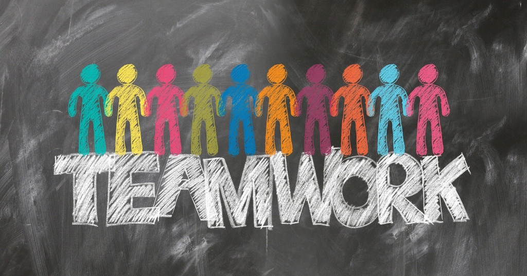 Chalkboard with the word team work written on it and people drawn in chalk