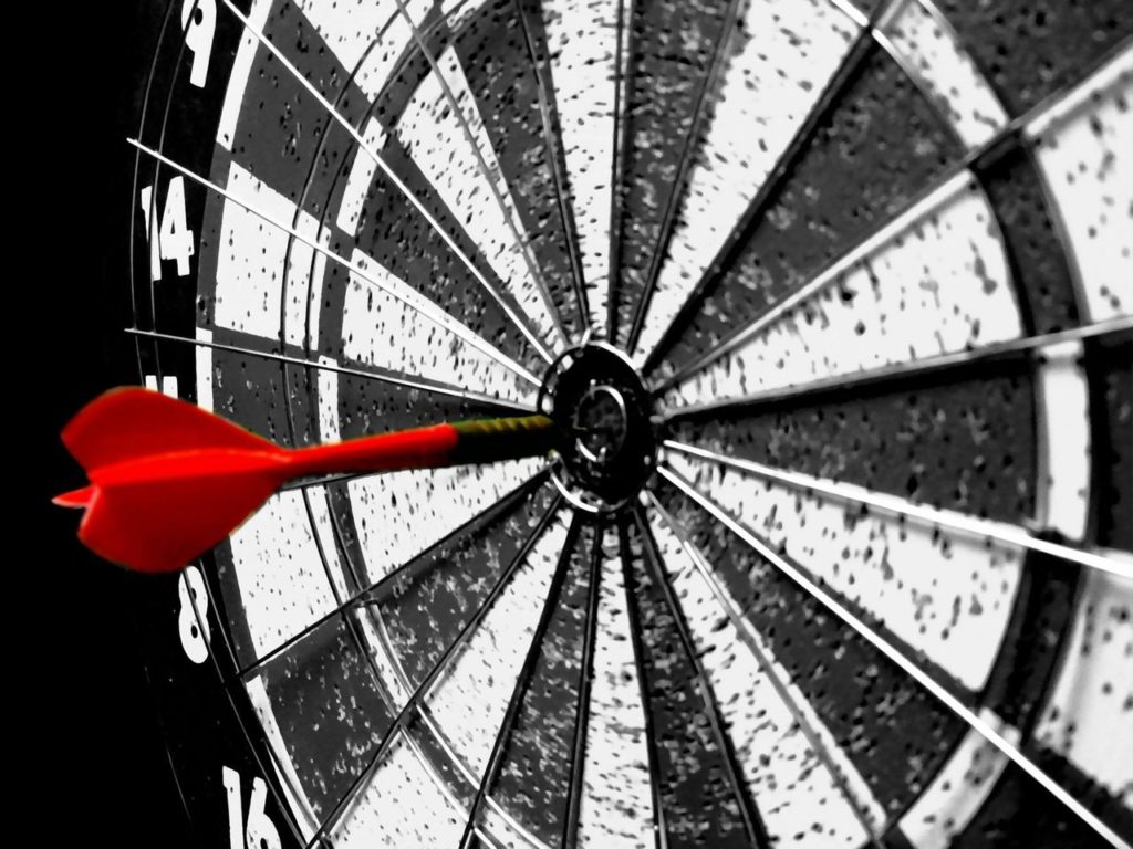 black and white dartboard with red dart in bullseye